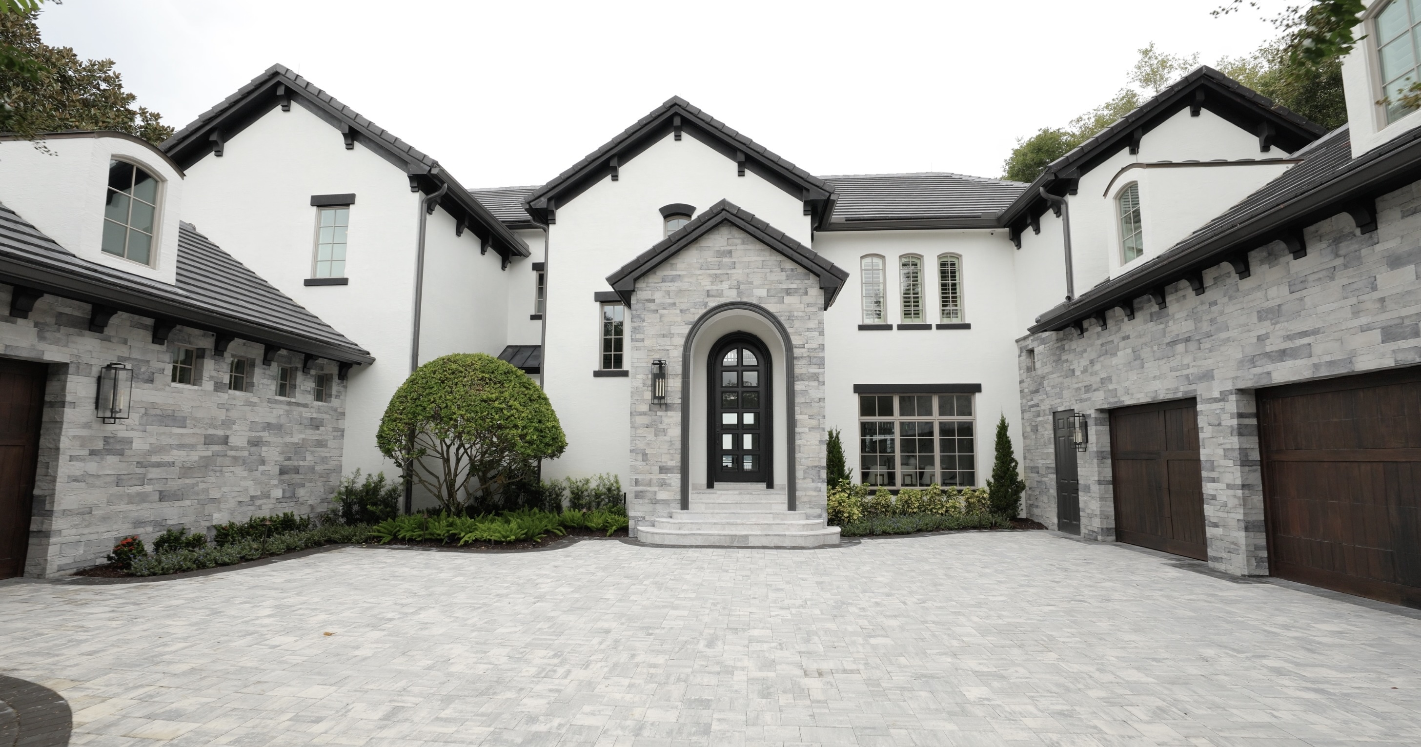 Front of luxury home with black and white paint and large driveway
